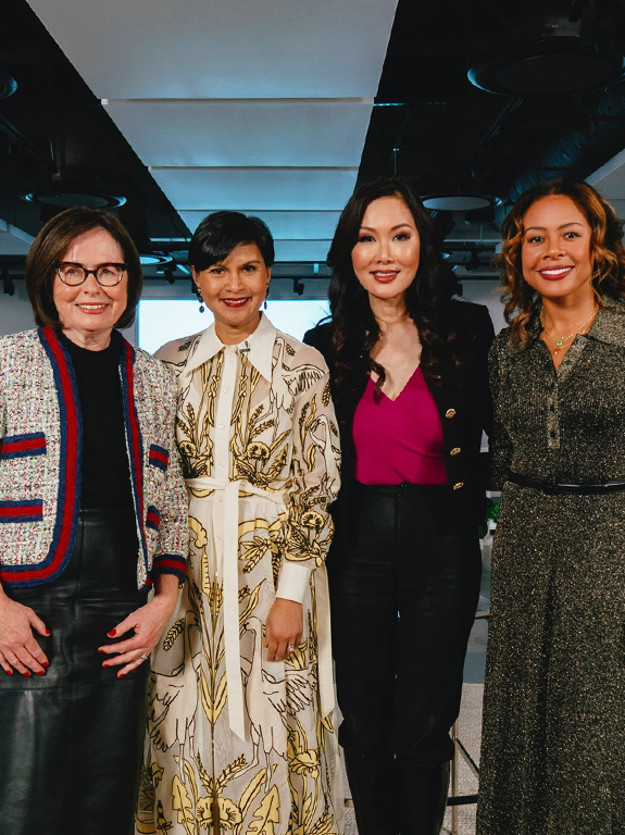 Four elegant, smiling women in an office space