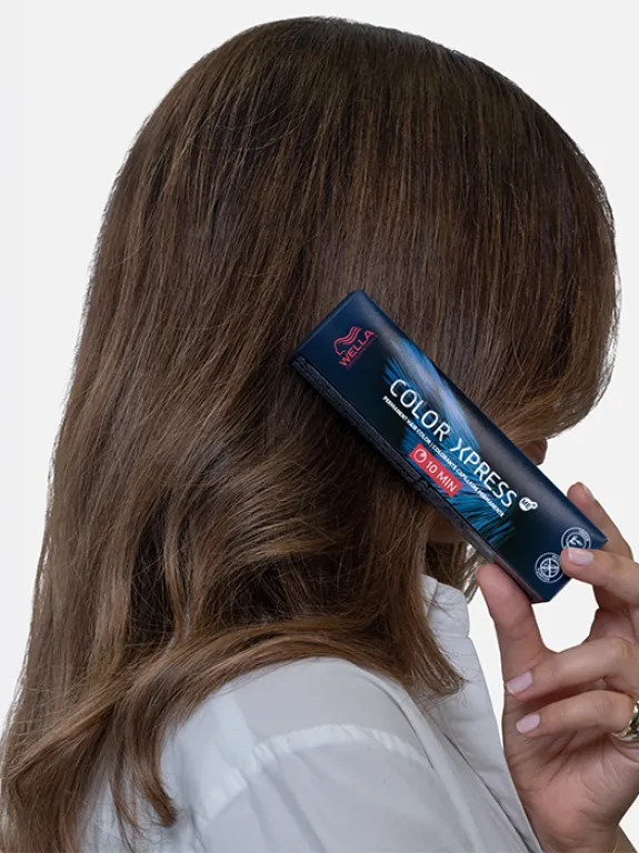 Brunette shows off her intense hair color while holding a box of Wella Professionals Color Xpress