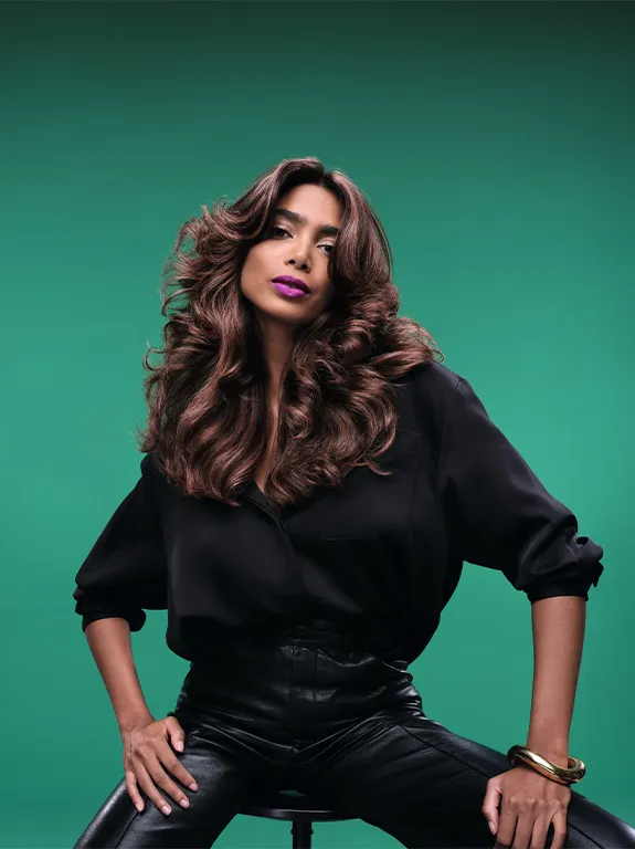 Woman with long shiny wavy hair on a green background