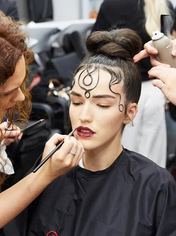 Model undergoing professional make-up and hair styling