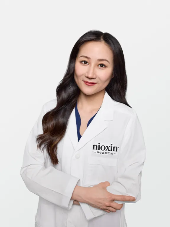 Dr. Liu smiling in white lab coat with Nioxin patch