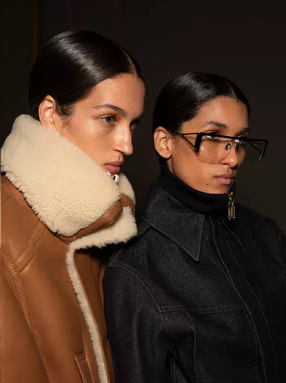 Two fashion models against a dark background