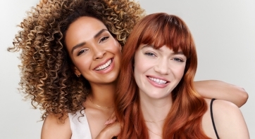 Two smiling women on a gray background