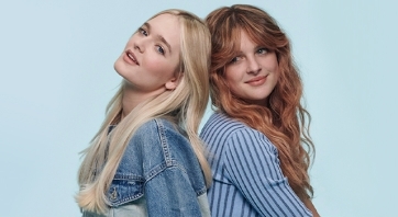 Two women in bluish clothes on a sky blue background