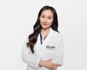 Dr. Liu smiling in white lab coat with Nioxin patch